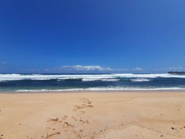 Endonezya 'nın doğu Java bölgesindeki Sogo plajında dalgalarla ve mavi gökyüzüyle deniz manzaralı bir kumsal..