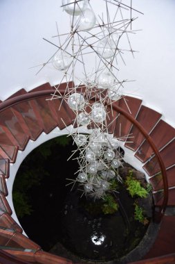 Ahşap merdivenleri ve havada asılı bir lambası olan binanın iç görüntüsünün dikey görüntüsü.