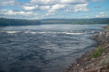 Bulutlu gökyüzünün altında huzur dolu göl manzarası.