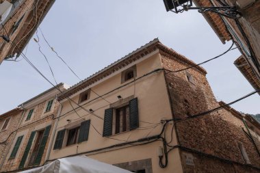 Bunyola, Mallorca 'da eski taş binaların alçak açılı bir görüntüsü ve açık kablolar.