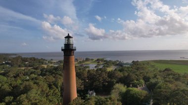 Currituck Sahili Deniz feneri Corolla, Kuzey Carolina 'da yemyeşil ağaçlarla çevrili.