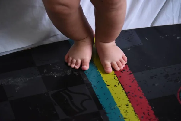 A closeup shot of the cute feet of a baby on a black floor