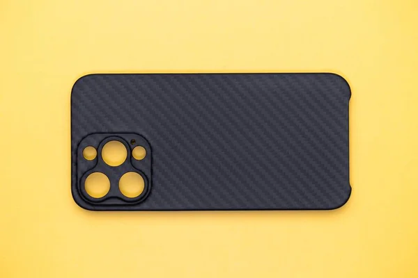 Black phone case. Phone made of a kevlar mix. Isolated case on yellow background