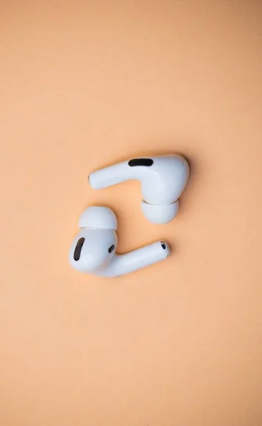 Eine Vertikale Aufnahme Von White Wireless Kopfhörern Isoliert Auf Orangefarbenem — Stockfoto