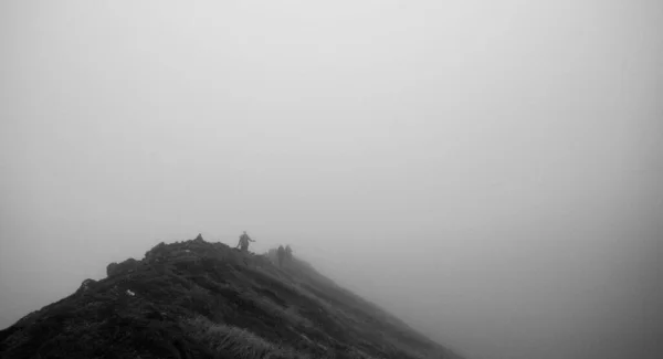 Een Grijswaarden Shot Van Wandelaars Lopend Mee Een Heuvelrug Mist — Stockfoto