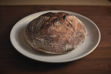 Fırından çıkmış ahşap bir masanın üzerinde mükemmel bir ekşi ekmek..