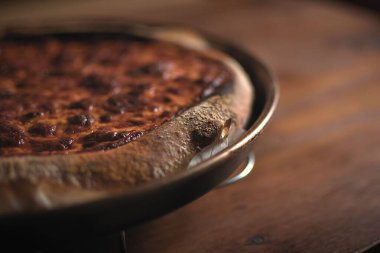 Fırına girmeden önce ahşap bir masanın üzerinde mükemmel bir ekşi ekmek tarzı pizza..