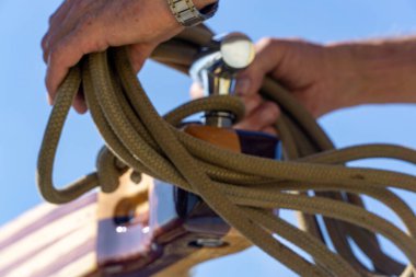 Bir adamın eli halatı geminin sapına koyuyor.