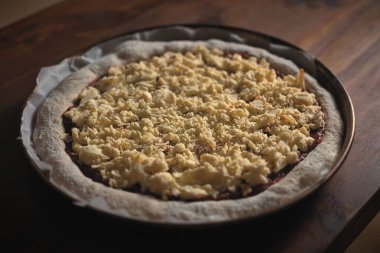 Fırına girmeden önce ahşap bir masanın üzerinde mükemmel bir ekşi ekmek tarzı pizza..