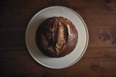 Fırından çıkmış ahşap bir masanın üzerinde mükemmel bir ekşi ekmek..