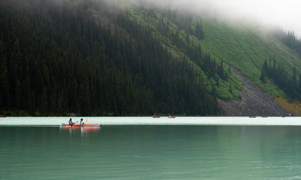 Каноэ Двумя Людьми Плывущими Озере Луиза Возле Холмов Деревьями Альберте — стоковое фото