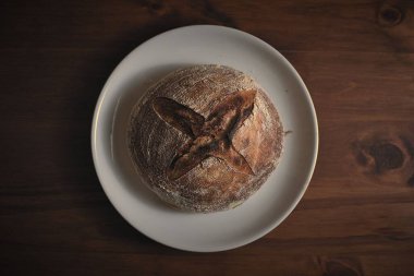 Fırından çıkmış ahşap bir masanın üzerinde mükemmel bir ekşi ekmek..