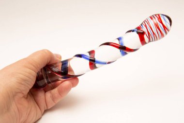 A person's hand holding Sex Toy swirly ribbed glass dildo on white background