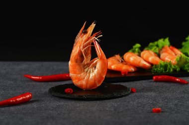 Kırmızı biberin yanında yeşil marul yaprağı olan karideslerin yakın çekimi.