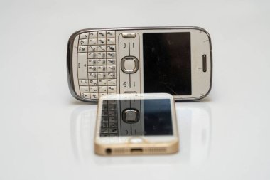 Beyaz arka planda iki tane hasarlı akıllı telefon.