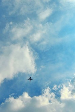 Mavi bulutlu gökyüzünde uçan bir uçağın dikey alçak açılı görüntüsü