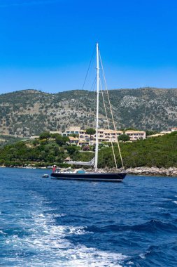 Arka planda güzel bir iskan kıyı şeridi olan bir yatın dikey görüntüsü.