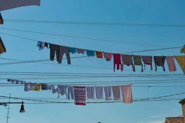 İtalya, Venedik 'te mavi bir gökyüzüne karşı güneş ışığı altında kurumuş çamaşırların düşük açılı bir çekimi.