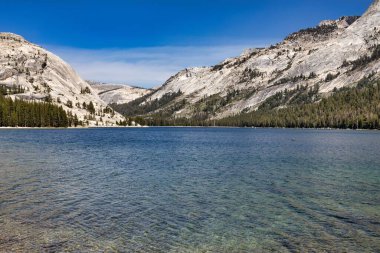 Güneşli bir günde mavi göl kenarındaki kar manzarası.