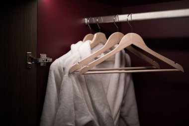 Bornozlar kırmızı duvarlı bir dolapta asılı.