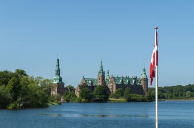 Ağaçlarla çevrili bir gölün kıyısındaki Frederiksborg Kalesi 'nin güzel manzarası.