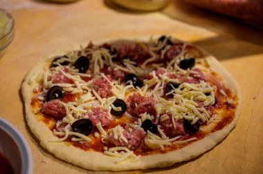 Tahta masadaki çiğ pizzanın yakın çekimi.