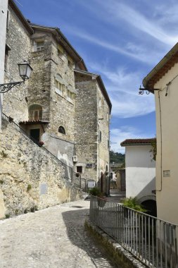 İtalya 'nın Fontana Liri köyündeki eski evler arasındaki dar asfalt bir caddenin dikey görüntüsü.