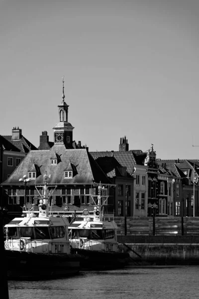 ヴリシンゲンを背景に伝統的な家屋がある水上のボートの垂直グレースケール — ストック写真