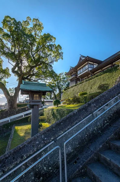 A vertical shot of a terraced garden with a buildings with triangular roofs on the horizon