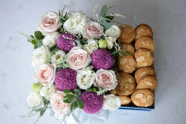 A top view of a flower bouquet of colorful roses and chrysanthemums with cookies