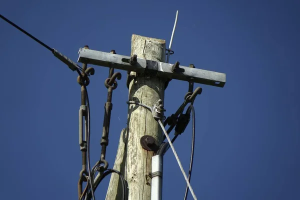 电线和旧木制电线杆顶部 再加上蓝色春天里右边的小蜘蛛网 — 图库照片