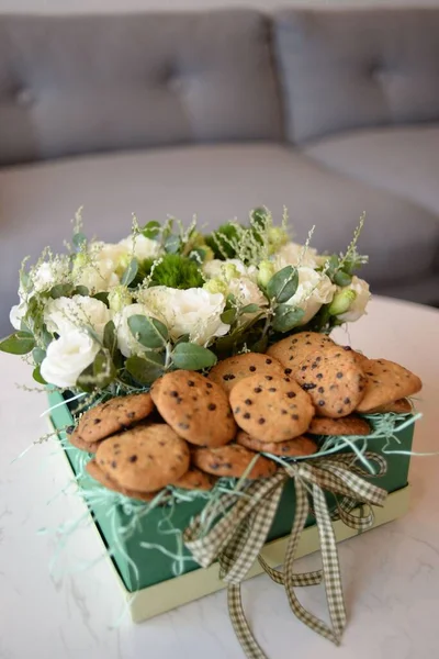 テーブルの上にクッキーと白いバラの花の花束の垂直ショット — ストック写真