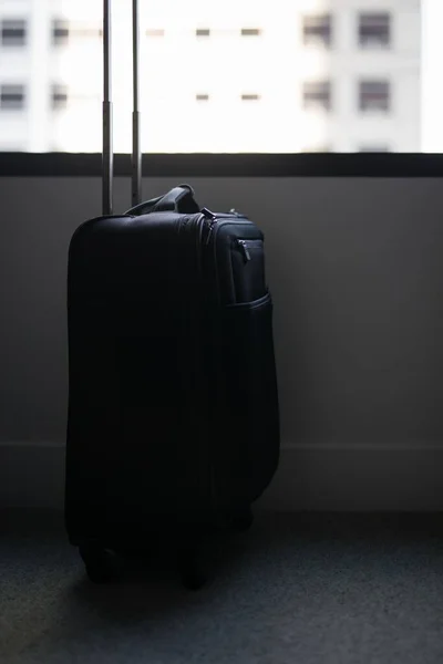 バルコニーに立っている黒いスーツケースの垂直ショット — ストック写真