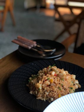 Siyah tabakta doğranmış karides ve sebzeli pilav.