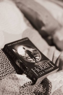 Yatak çarşafında yatan Hobbit kitabının dikey gri pulu