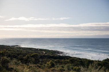Sakin bir deniz ve bulutlu bir günde kayalık bir sahil.