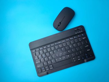 Mavi arkaplanda siyah bir bluetooth kablosuz klavye ve kablosuz fare