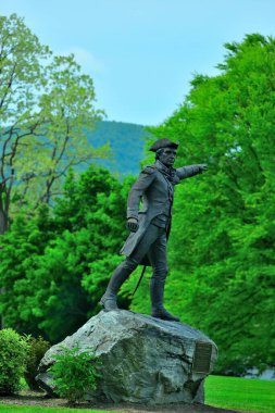 General John Stark 'ın Vermont, ABD' deki canlı yeşil ağaçlara karşı heykelinin dikey çekimi.