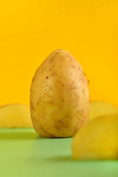 黄色の背景にジャガイモの垂直ショット — ストック写真