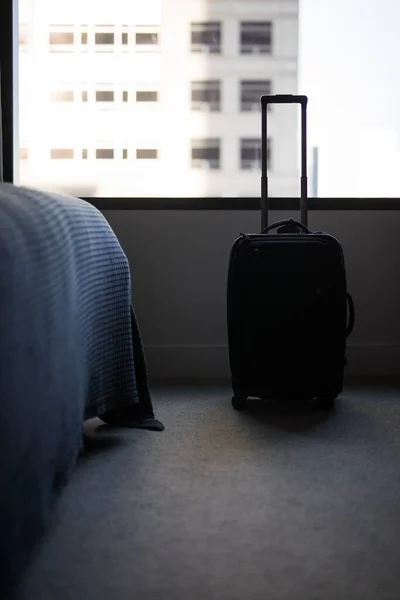 Eine Vertikale Aufnahme Eines Schwarzen Koffers Auf Dem Schlafzimmerboden — Stockfoto