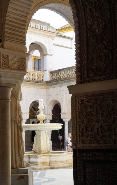 A vertical shot of a fountain in the yard of an old medieval building with beautiful decorations