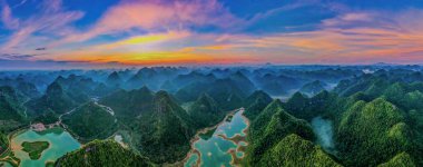 Yangshuo County, Çin 'de gün batımında bir nehirle çevrili dağların hava manzarası.