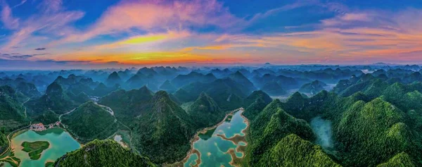 Yangshuo County, Çin 'de gün batımında bir nehirle çevrili dağların hava manzarası.