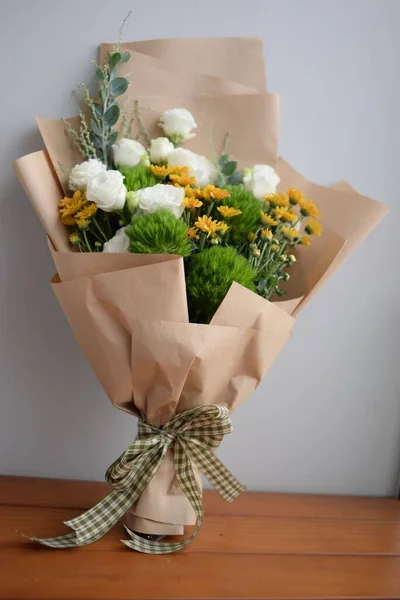一束白色玫瑰和橙黄色雏菊的花束与包裹在一起的垂直照片 — 图库照片