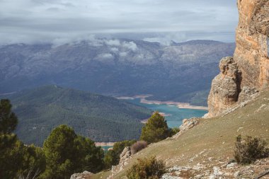 Yeşil bir manzaraya, mavi bir göle ve dağlara tepeden bakan güzel bir görüntü.