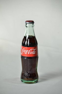 Beyaz arka planda bir stüdyoda bir şişe Coca-Cola 'nın dikey çekimi.