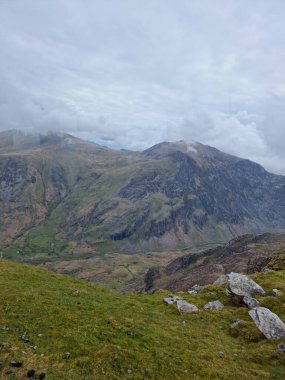 Baharda dağın kayalık vadisinde bulutlu gökyüzünün dikey görüntüsü.