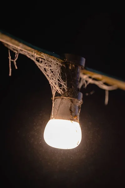 Vertikální Záběr Staré Špinavé Lampy Zavěšené Dřevěné Tyči Tmavém Pozadí — Stock fotografie