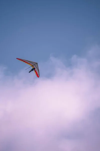 真っ青な空に赤い線が美しい雲とハンググライダーの垂直ショット — ストック写真