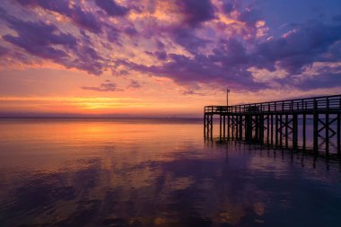Gün batımında iskelesi olan güzel bir deniz manzarası büyüleyici.